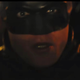 The Batman looks on in shock and concern while driving the Batmobile.